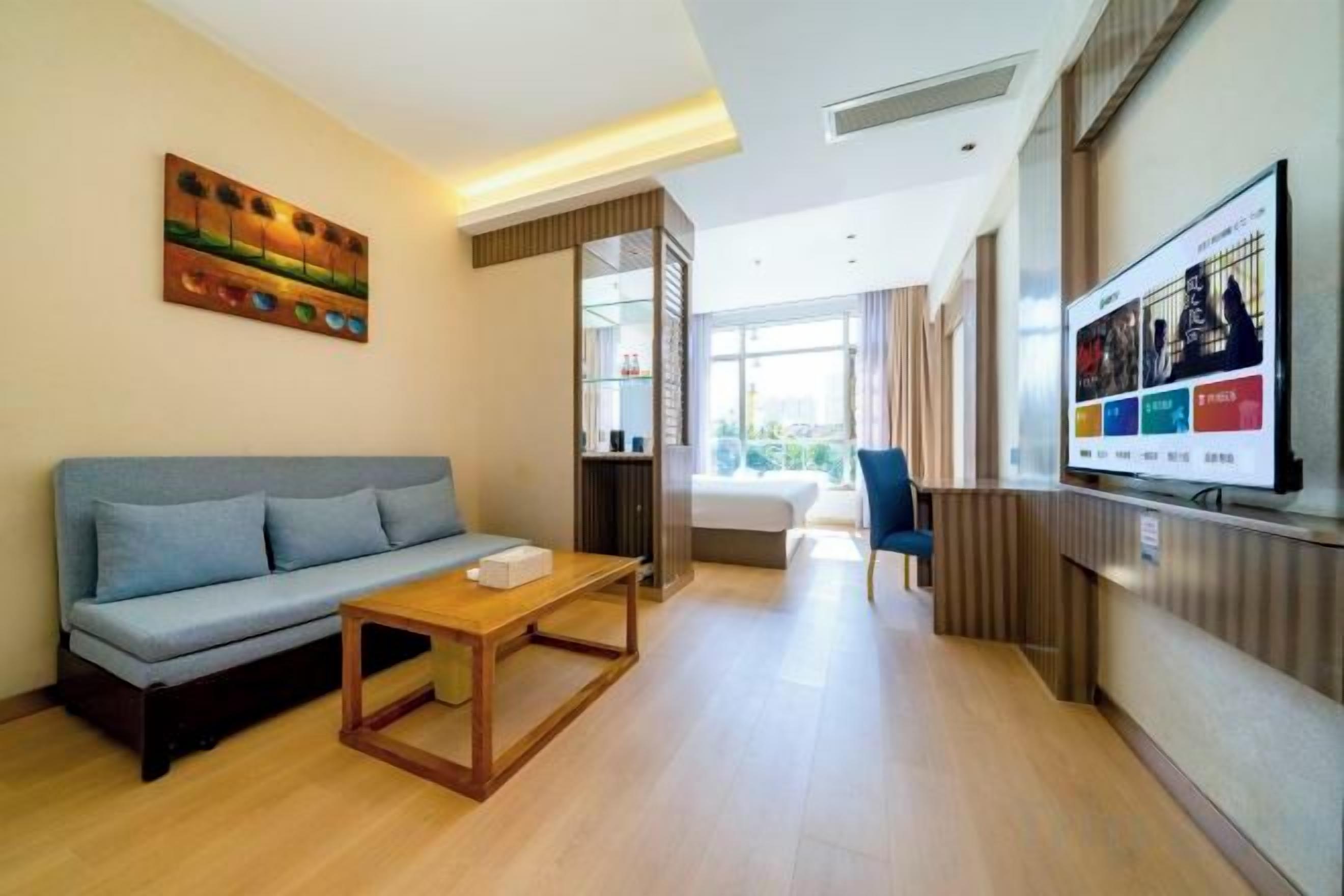 A modern living room with a sofa, coffee table, and a flat-screen TV mounted on the wall.