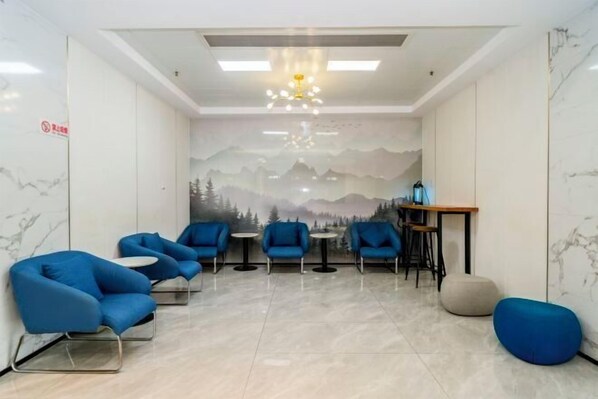 A modern waiting area with blue chairs, a small round table, and a mural of mountains on the wall. - Jingdu Hotel (Quanzhou West Street Overseas Chinese History Museum Branch) (Quanzhou)