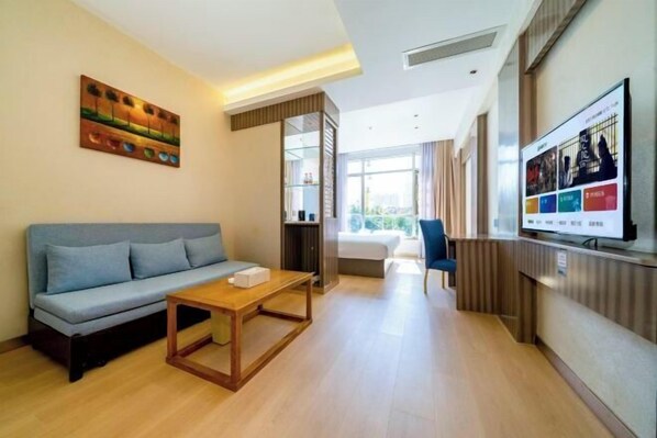 A modern living room with a sofa, a coffee table, a TV, and a painting on the wall. - Starway Hotel (Fengze Plaza Donghu Street) (Quanzhou)