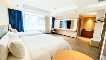 A hotel room with two beds, a TV, a small kitchenette, and a view of the city.