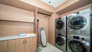 Ein Waschraum mit Holzausstattung, einem Wäscheständer und gestapelten Waschmaschinen.
