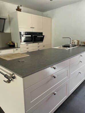 Una cocina moderna con armarios blancos, electrodomésticos de acero inoxidable y encimera gris.