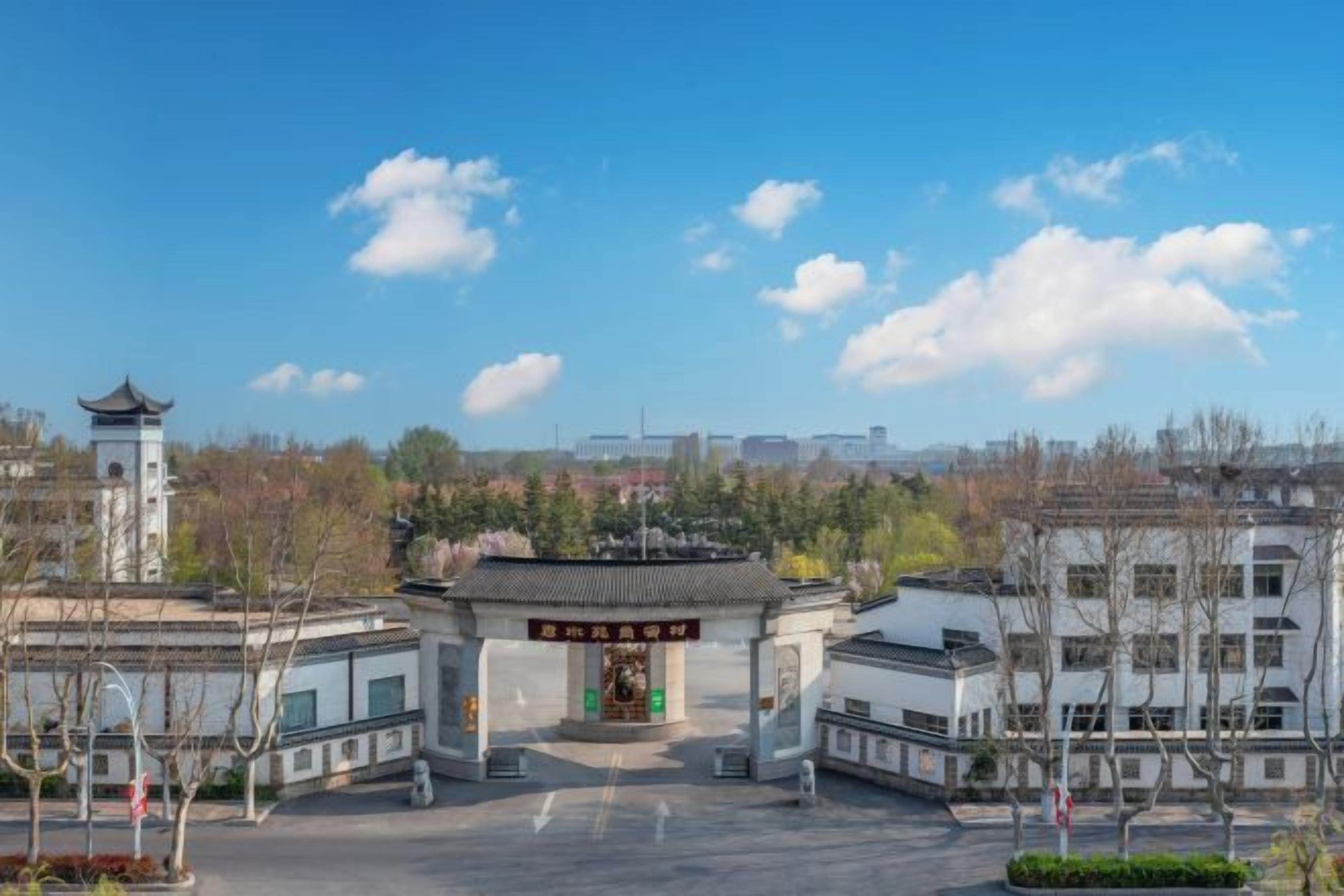 A traditional gate with a clear sky and distant buildings.