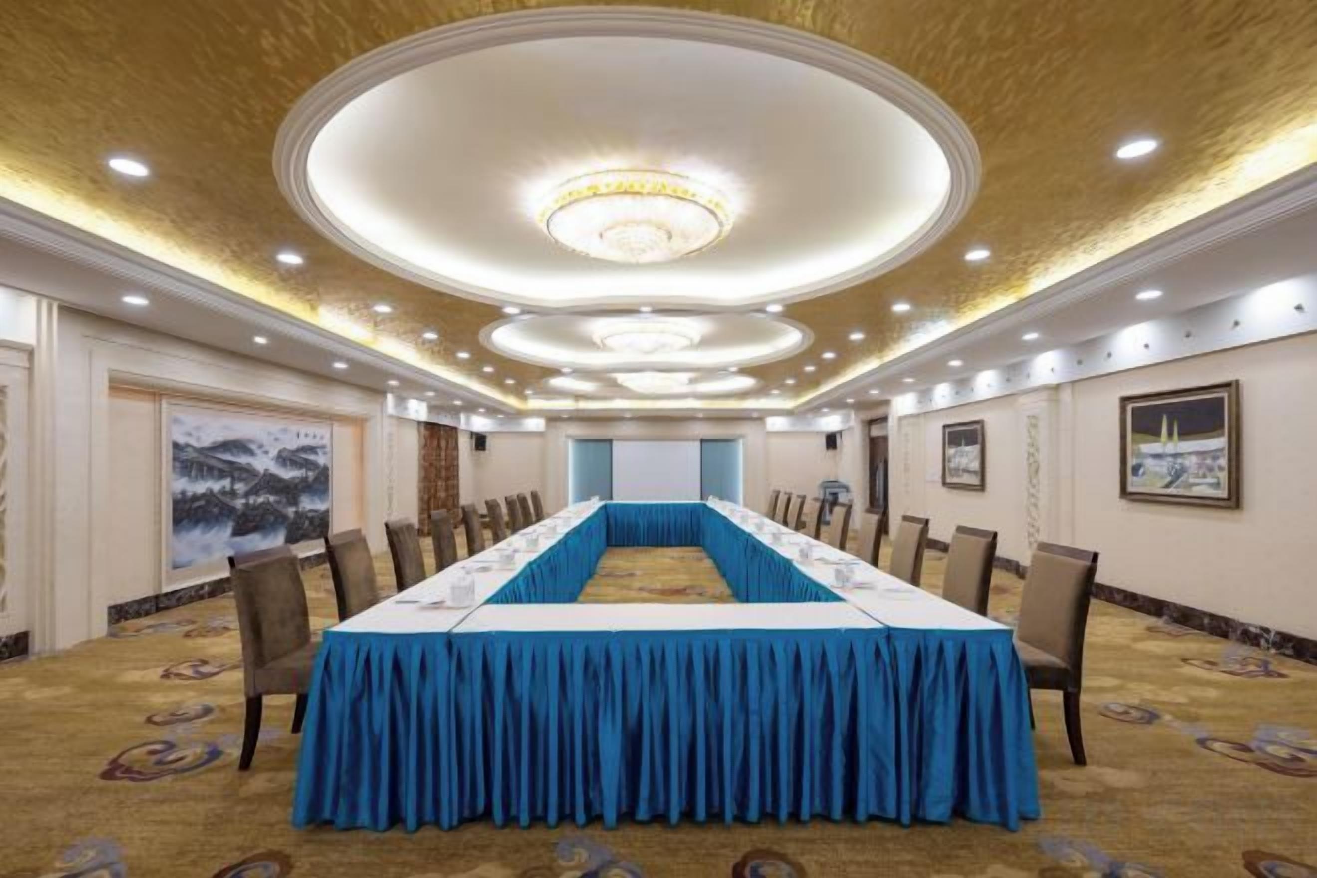 A conference room with a long table, chairs, and a carpeted floor.