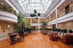 A spacious lobby with a high ceiling, multiple seating areas, and indoor plants. - Qingdaojinxiushui Hotel (Pingdu)