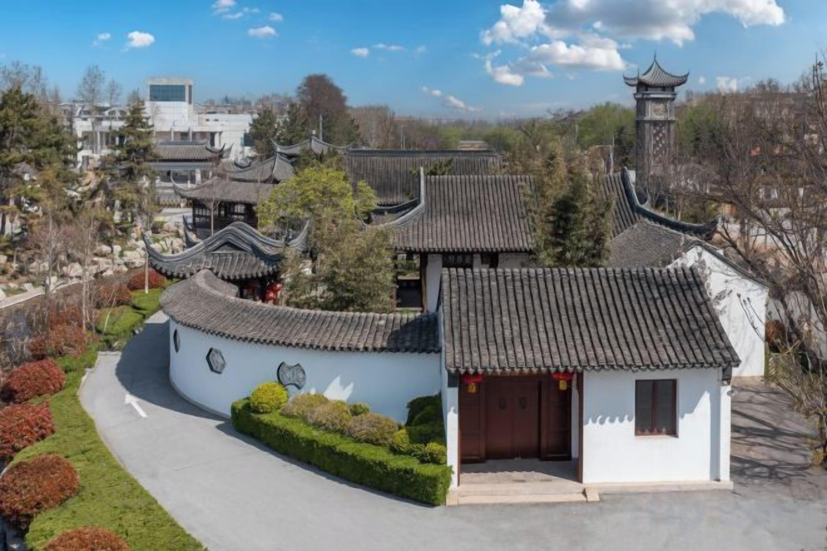 A traditional building with curved roofs and a small entrance, surrounded by well-maintained greenery.