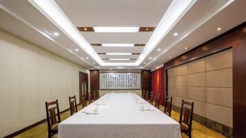 Un salón de conferencias con una larga mesa, sillas y un techo alto con iluminación empotrada.