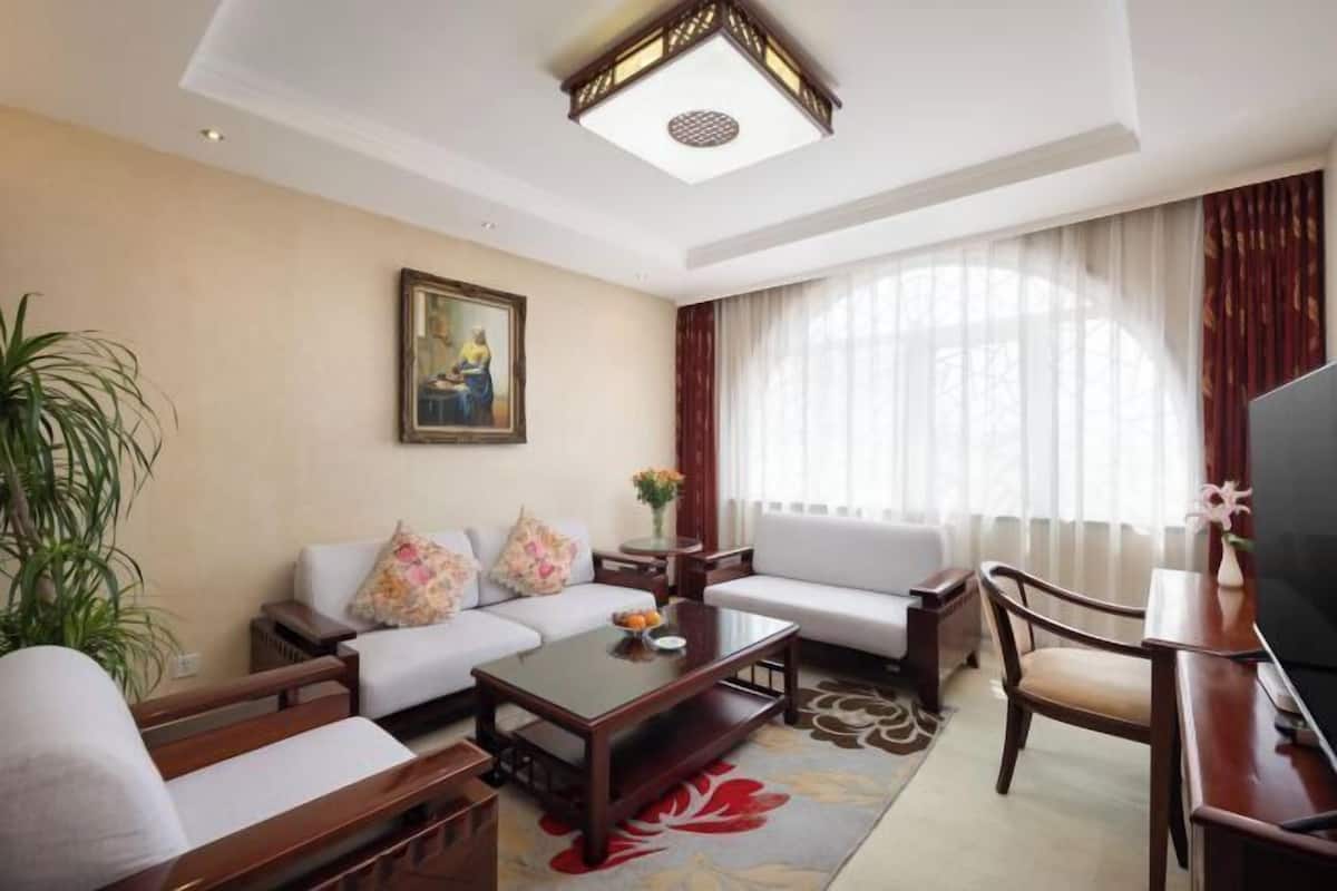 A living room with a sofa, armchairs, a coffee table, a TV, and a painting on the wall.