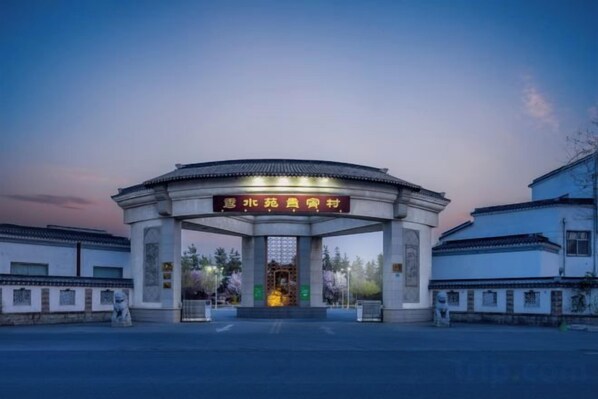 A traditional Chinese gate with a sign, surrounded by white buildings and a clear sky. - Qingdaojinxiushui Hotel (Pingdu)