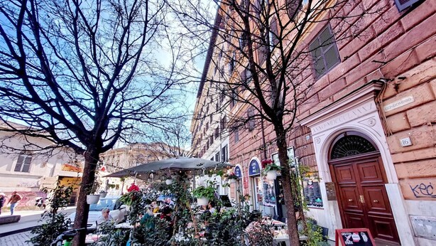 A street view with a café surrounded by trees and buildings.
