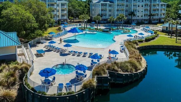 A resort with a large central pool, multiple smaller pools, and a variety of lounge areas with umbrellas. - RBC 2 Heritage Golf Week 2-BR resort Hilton Head Island - AC, WiFi, fitness room (Hilton Head Island)