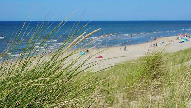 Une plage avec des gens, des tentes et un bateau.
