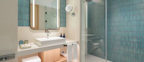 A modern bathroom with a glass shower enclosure, a white sink, and a large mirror.