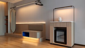 Quarto moderno com banco embutido, espelho fixado na parede e frigorífico embutido.