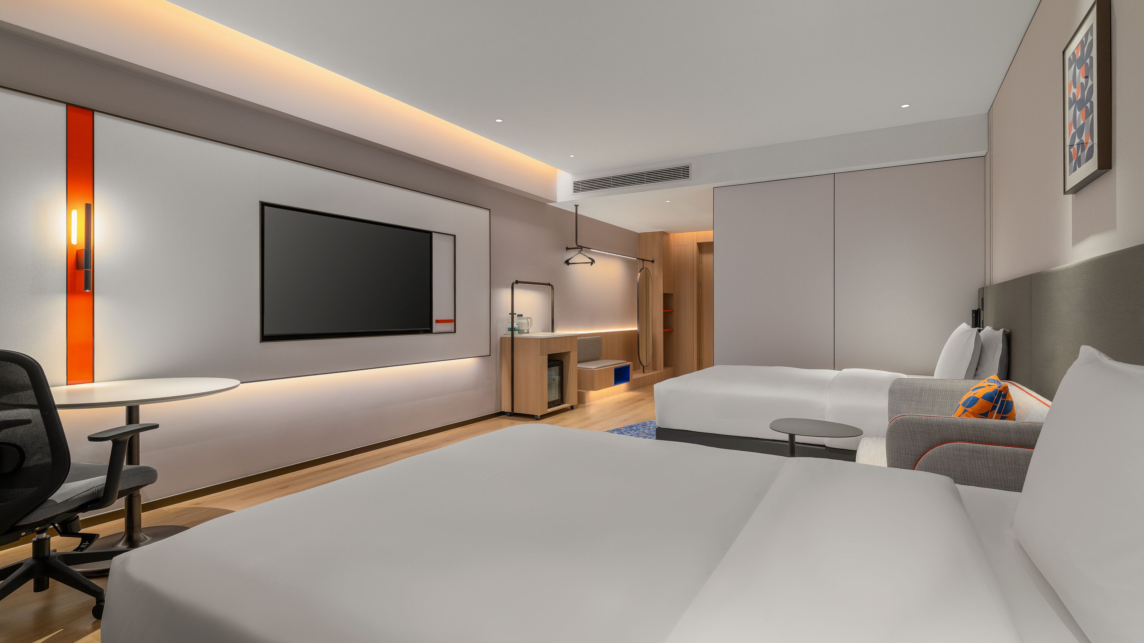 Una habitación de hotel moderna con una cama grande, un escritorio, una silla, un televisor y una mesita.