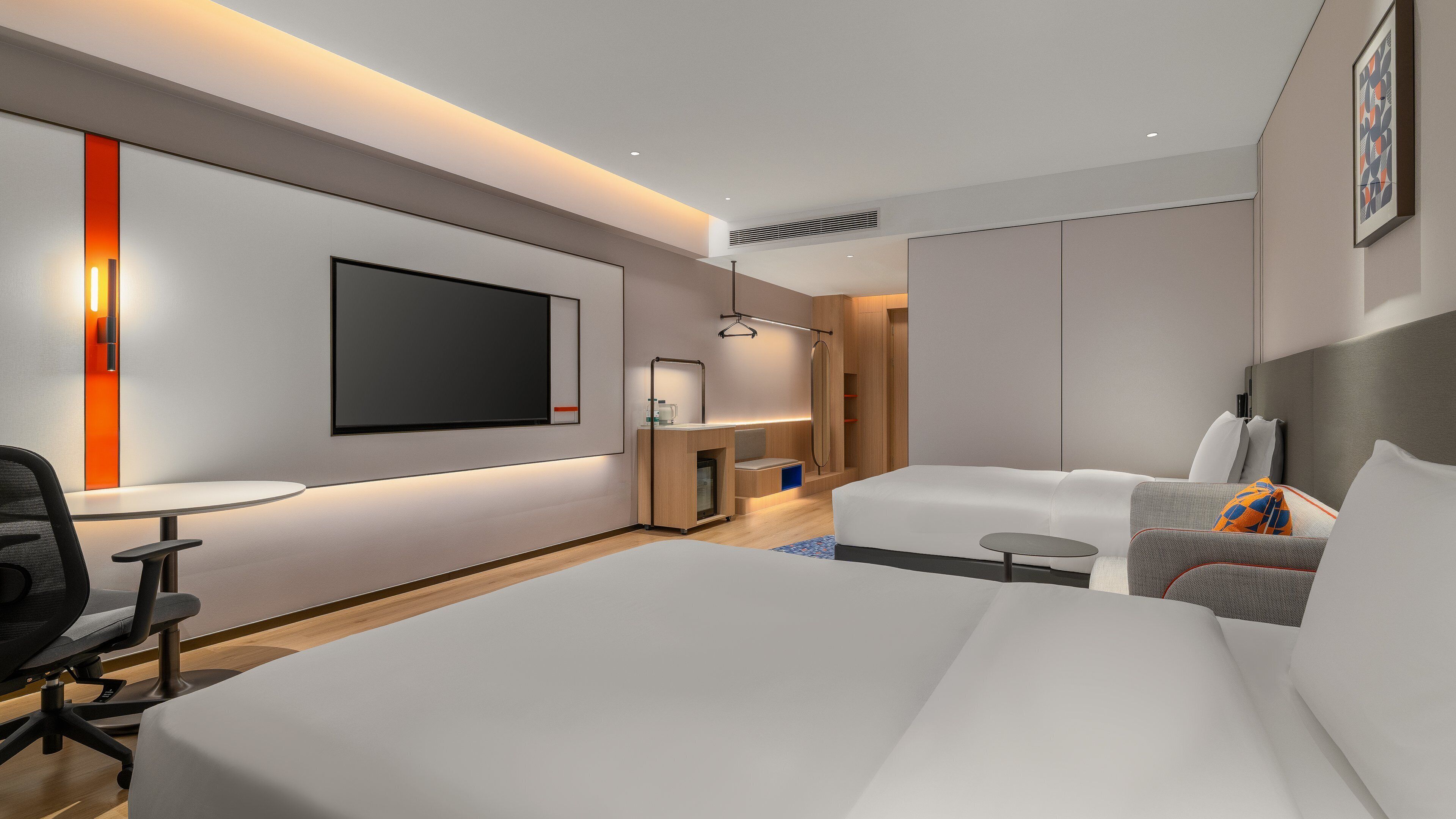 Une chambre d’hôtel moderne équipée d’un grand lit, d’un bureau, d’une télévision et d’un coin salon.