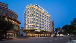 Um hotel Holiday Inn Express de vários andares com fachada curva, janelas amplas e uma placa bem visível.