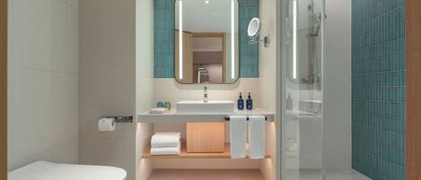 A modern bathroom with a toilet, sink, mirror, and shower.