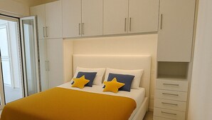 A bedroom with a bed, white cabinets, and a sliding door. - Cozy beach house 150 mt from the beach kitchen and shower also outside (Nocera Scalo)