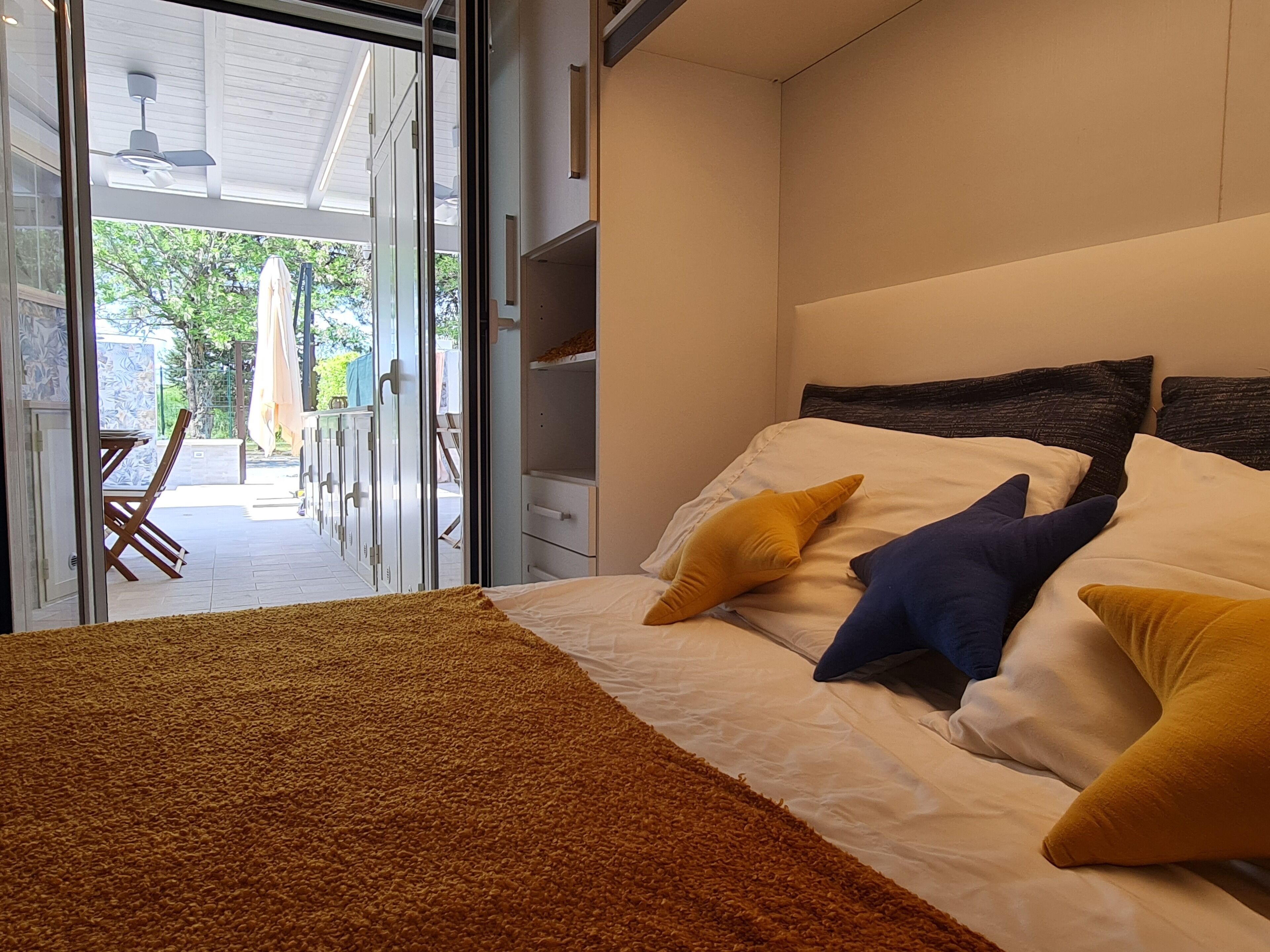 Un dormitorio con cama, alfombra marrón y vistas a un patio exterior.
