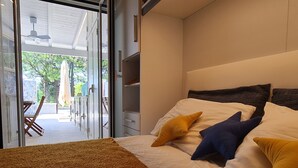 A bedroom with a bed, a brown carpet, and a view of an outdoor patio area. - Cozy beach house 150 mt from the beach kitchen and shower also outside (Nocera Scalo)