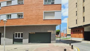 Un edificio de varios pisos con fachada de ladrillo y una puerta de cochera que dice 'ROOMS'.