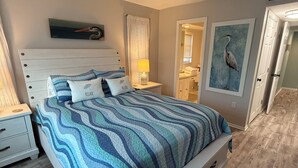 A bedroom with a bed, nightstands, a ceiling fan, and artwork on the walls. - Island Time - 2 Minute Walk To The Beach & Heated Pool (Holmes Beach)