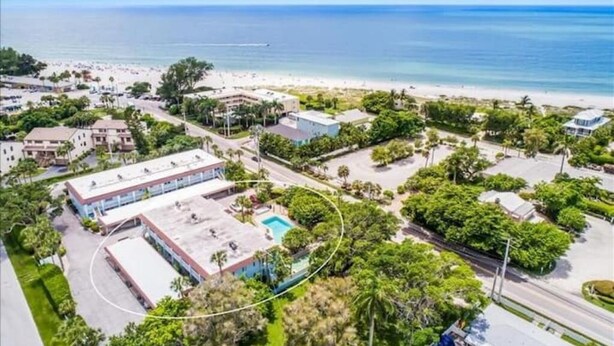 An aerial view of a coastal area with a beach, buildings, and a swimming pool. - Island Time - 2 Minute Walk To The Beach & Heated Pool (Holmes Beach)