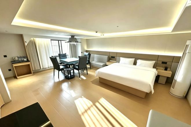A modern hotel room with a large bed, a desk, and a chair.