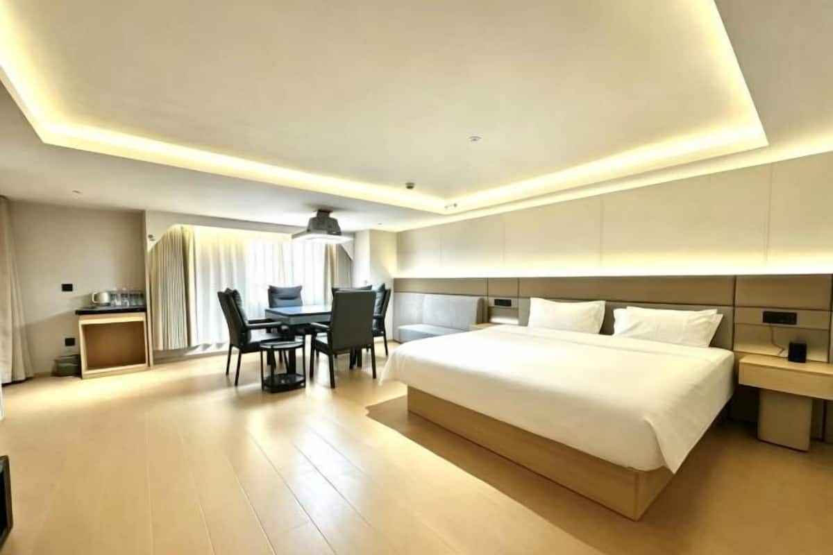 A modern hotel room with a large bed, a desk, and a chair.