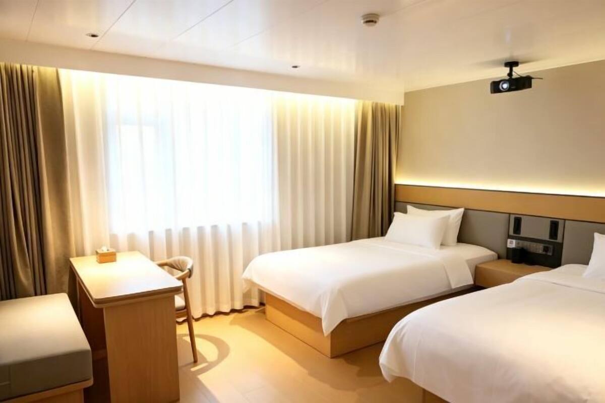 A hotel room with two beds, a desk, and a chair.
