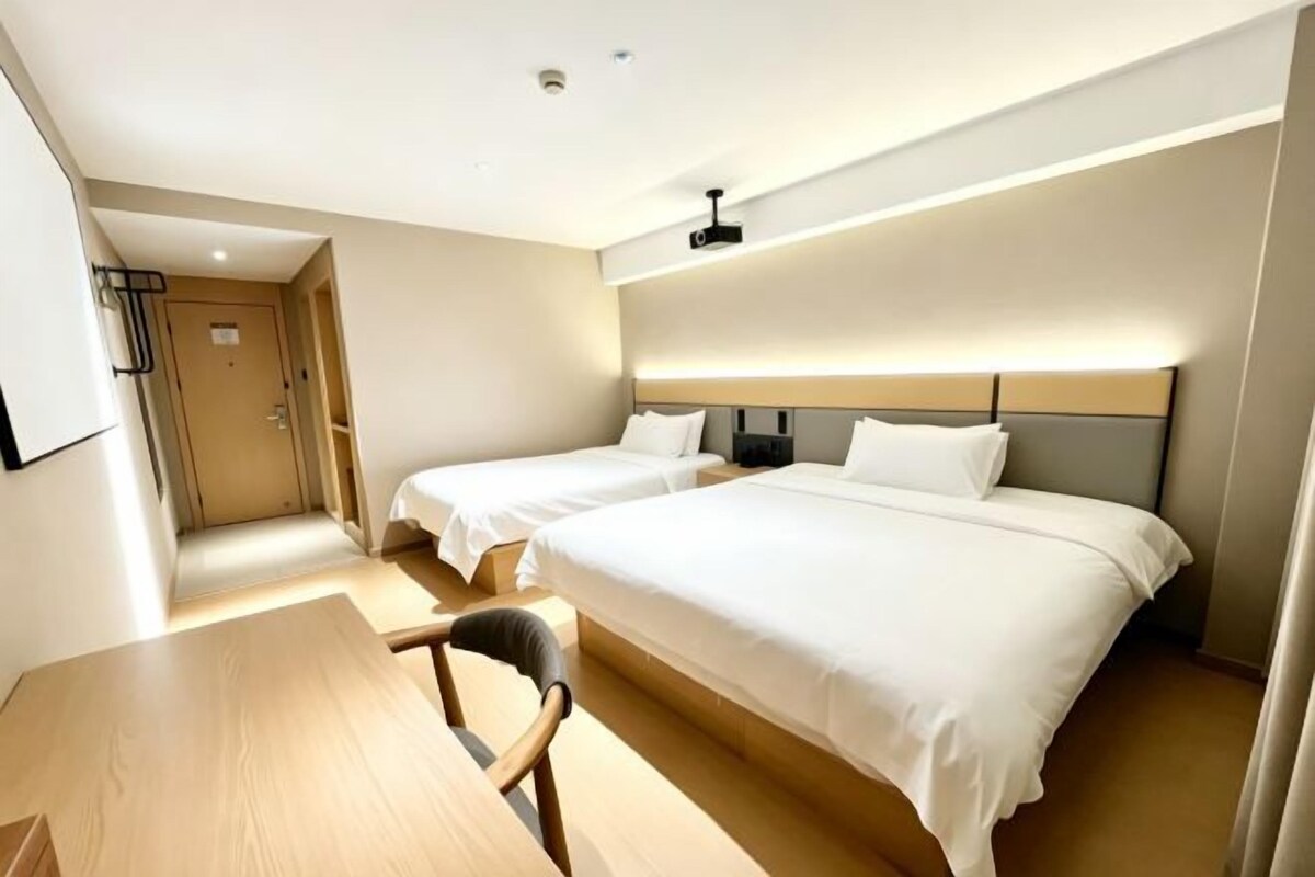 A hotel room with two beds, a desk, and a chair.