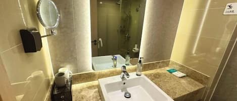 A hotel bathroom with a sink, mirror, and shower.