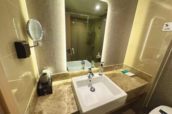 A hotel bathroom with a sink, mirror, and shower. - Eman Hotel (Sanpailou Street Hongqiao Subway Station Branch) (Nanjing)