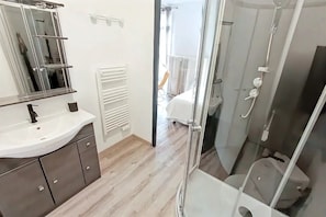 Ein modernes Badezimmer mit einer Duschkabine aus Glas, einem weißen Waschbecken und einem Spiegel.