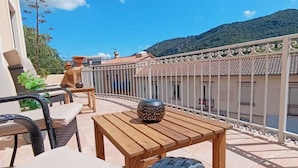 Une terrasse dotée de meubles en osier, d’une table en bois et d’un vase décoratif.