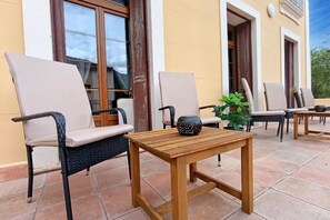 Eine Terrasse im Freien mit zwei Loungesesseln, einem Holztisch und einem Blumentopf.