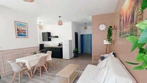 Un salon moderne avec un canapé, une table à manger, des chaises et un coin cuisine à l’arrière-plan.
