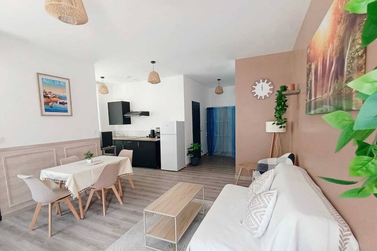 A modern living room with a sofa, dining table, chairs, and a kitchen area in the background.