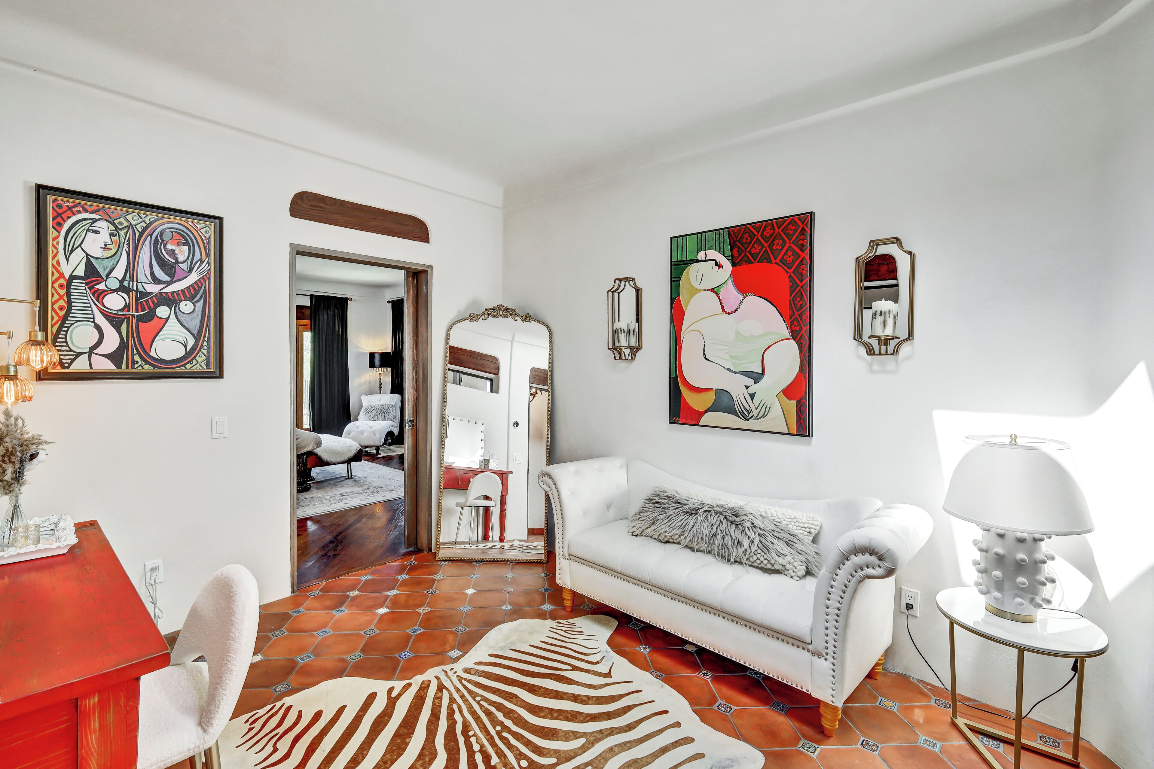 A modern living room with a white sofa, a red table, and a zebra-patterned rug.