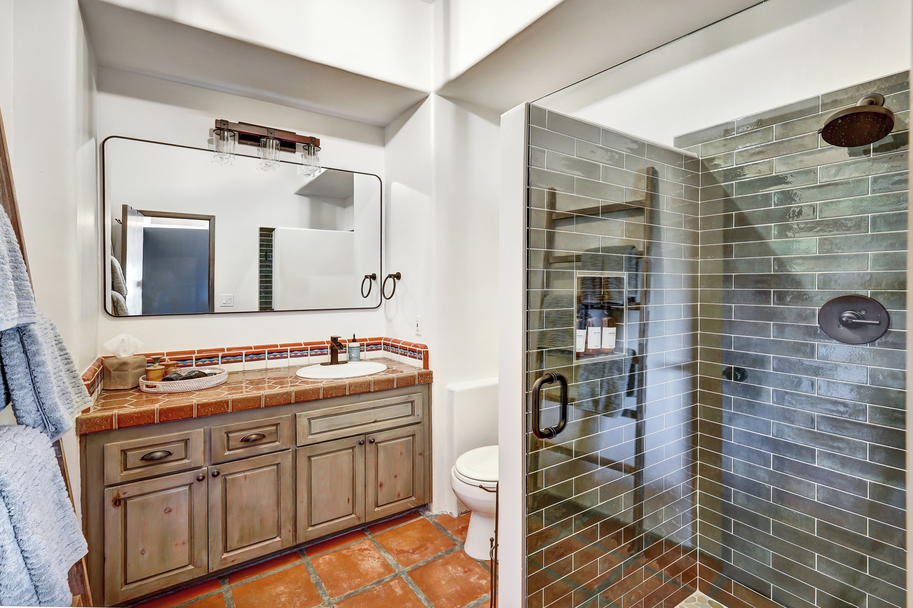 A bathroom with a glass-enclosed shower, a sink with a mirror above, and a toilet.