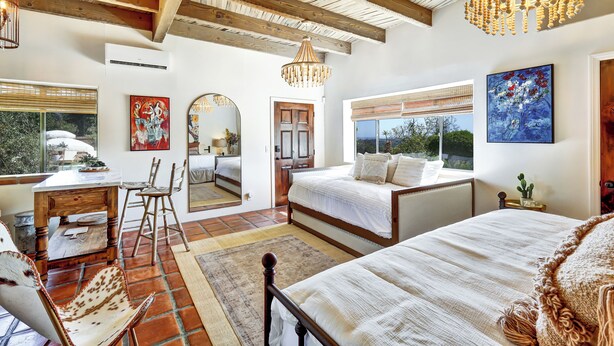 Un dormitorio con una cama grande, un escritorio y una silla. Un candelabro cuelga del techo.