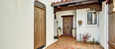 A courtyard with a tiled floor, a wooden door, and a covered entrance.