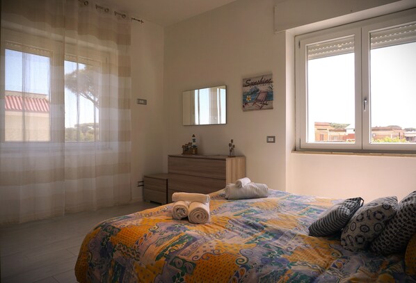 A bedroom with a bed, a dresser, a mirror, and a window.