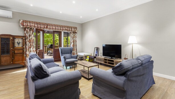 A living room with two grey sofas, a coffee table, a TV, and a lamp. - Birdstow – Spacious, peaceful Stay, Sleeps 10 (Wentworth Falls)