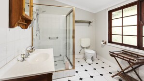 A bathroom with a white sink, a glass-enclosed shower, a white toilet, and a window with a view. - Birdstow – Spacious, peaceful Stay, Sleeps 10 (Wentworth Falls)