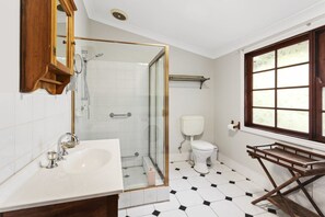 A bathroom with a white sink, a glass-enclosed shower, a white toilet, and a window with a view. - Birdstow – Spacious, peaceful Stay, Sleeps 10 (Wentworth Falls)
