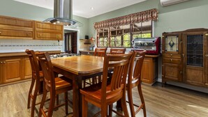A spacious kitchen with wooden cabinets, a large dining table, and a built-in grill. - Birdstow – Spacious, peaceful Stay, Sleeps 10 (Wentworth Falls)