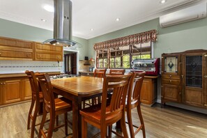 A spacious kitchen with wooden cabinets, a large dining table, and a built-in grill.