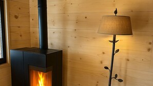 A wood-burning stove with a visible fire, a lamp, and a wooden wall.